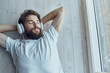 © SHOTPRIME STUDIO - man in white t-shirt lying near the window wearing headphones technology