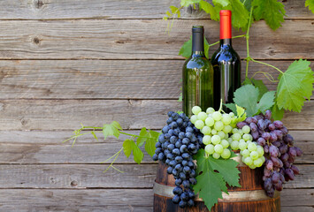 Wall Mural - Various colorful grapes and wine bottles on wine barrel