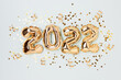 2022 gold foil balloons and confetti on a blue pastel background. Holidays concept.