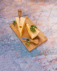 Wall Mural - Maasdam cheese on wooden board with basil sprigs