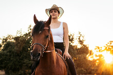 Woman Riding Horse On Path At Sunset