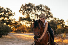 Woman Riding Horse On Path At Sunset