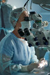 © ADDICTIVE STOCK - Surgeon looking through microscope against crop assistant in clinic