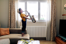 Girl Playing Saxophone On Sofa In House Room