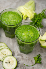 Wall Mural - Green juice and ingredients in glass on grey background