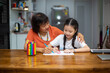 © Morakot - A portrait of a little Asian girl and her grandmother doing fun activities together at a happy home.