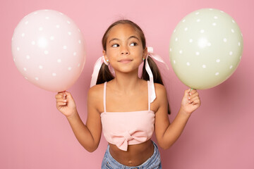 Wall Mural - Beautiful little girl with pastel colors air balloons isolated over pink background.