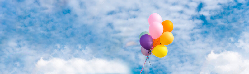 Wall Mural - Banner Cheerful cute girl holding balloons running green meadow white cloud and blue sky with happiness. Panorama Hands holding vibrant air balloons happy times summer sunlight outdoor copy space