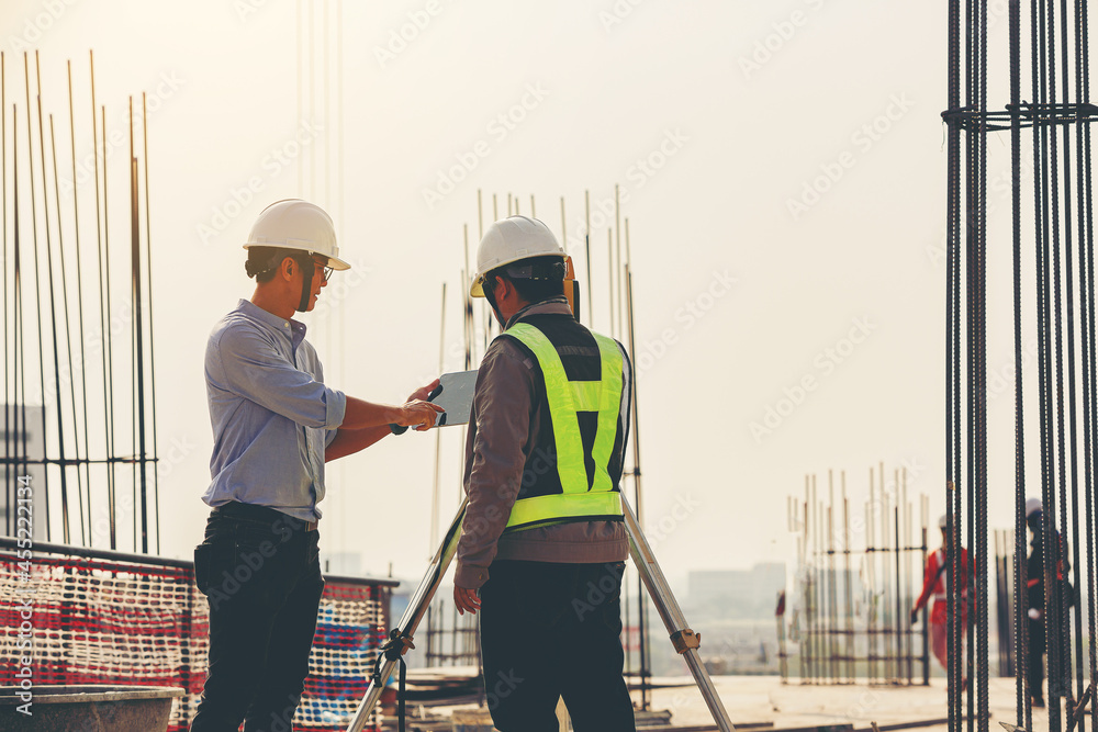 Structural engineer and foreman worker with touchpad discuss, plan inspecting for the outdoors building construction site.	