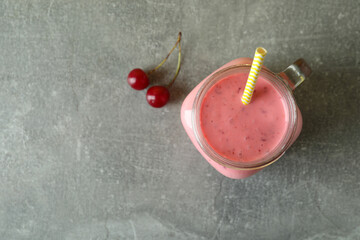 Wall Mural - Glass jar of cherry smoothie and ingredients on gray textured table