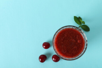 Wall Mural - Glass of cherry smoothie and ingredients on blue background