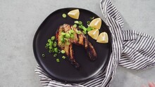 Grilled Salmon Steaks Garnished With Green Onions On A Black Plate.