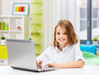 © Syda Productions - education, school and technology concept - happy smiling student girl with laptop computer learning online over home room background