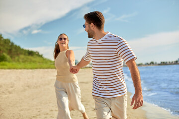 Wall Mural - summer holidays, leisure and people concept - happy couple running along beach