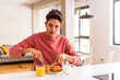 © Asier - Young mixed race man eating croissant in a kitchen on the morning