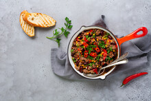 Traditional Mexican Food - Chili Con Carne With Minced Meat And Vegetables Stew In Tomato Sauce In A Cast Iron Pan On Light Gray Slate Or Concrete Background. Top View With Copy Space