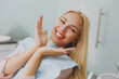 © ViDi Studio - Close up young amazed smiling happy woman covered by napkin spread hands sit at dental office chair indoor light modern cabinet wait stomatologist for oral procedure Healthcare caries enamel treatment