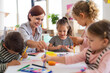 © Halfpoint - Group of small nursery school children with teacher indoors in classroom, painting.