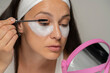© vladimirfloyd - portrait of a young woman with cosmetic product under her eyes applying mascara