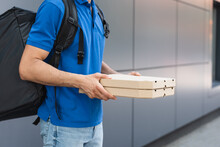 Cropped View Of Deliveryman With Backpack Holding Pizza Boxes Near Blurred Building Outdoors