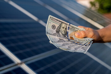 men's hands hold dollars as profit from the production of alternative energy. solar panels