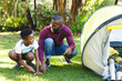 © wavebreak3 - African american father with son having fun pitching tent in garden