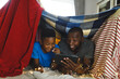 Happy african american father and son lying in blanket fort, using tablet