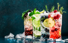 Cocktails Drinks. Classic Alcoholic Long Drink Or Mocktail Highballs With Berries, Lime, Herbs And Ice On Blue Background