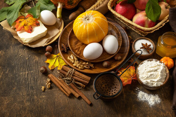 Wall Mural - Seasonal food autumn baking background - ingredients for baking (pumpkin, apples, eggs, flour, sugar and spices) on a wooden table. Copy space.