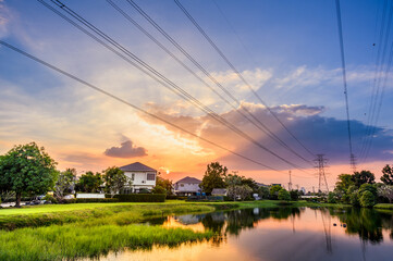 Line of high voltage power with electricity transmission close to residential buildings. Power transmission tower in city with urban area.