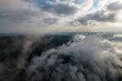 Foggy weather in mountains. Misty fog blowing over pine tree forest. Aerial view of spruce forest trees on the mountain hills at misty day. Morning fog at beautiful summer forest.