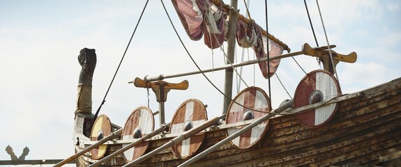 Old wooden viking snekkja longship type. Nautical vessel, tall ship, traditional craft, vintage, landmark, history, past, historical reenactment, nordic culture. Panoramic view