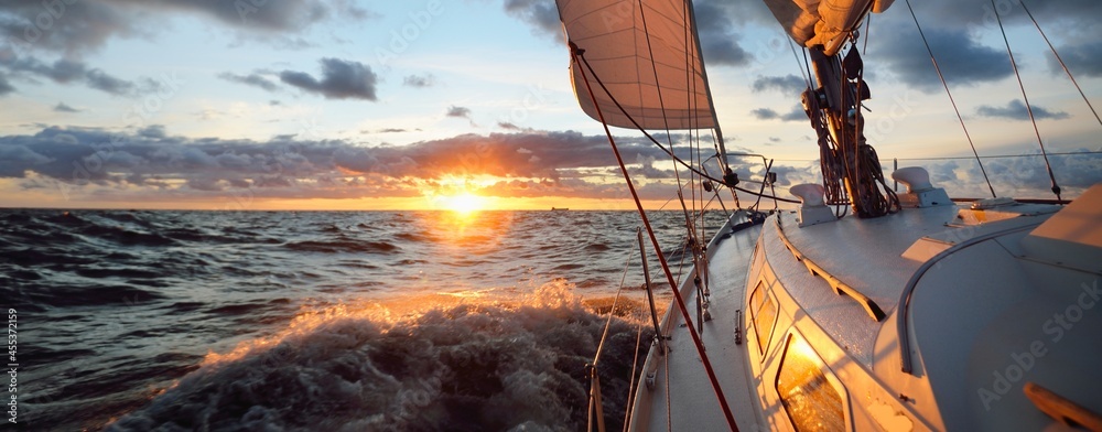 Yacht sailing in an open sea at sunset. Close-up view of the deck, mast ...