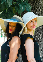 Canvas Print - Closeup view of black and caucasian women wearing hats and black t-shirts posing together