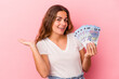 © Asier - Young caucasian woman holding bills isolated on pink background  showing a copy space on a palm and holding another hand on waist.