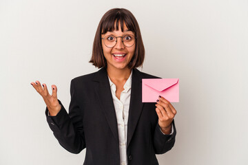 Young mixed race business woman holding a letter isolated on white background receiving a pleasant surprise, excited and raising hands.