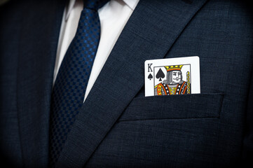 A poker king card in the pocket of a suit.