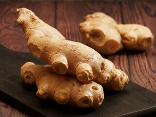 Wall Mural - Ginger root on a burned wood cutting board over brown wood background