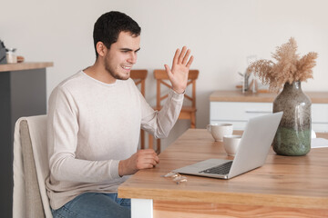 Sticker - Young man with laptop video chatting in kitchen