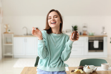 Wall Mural - Beautiful young woman with tasty chocolate paste at home