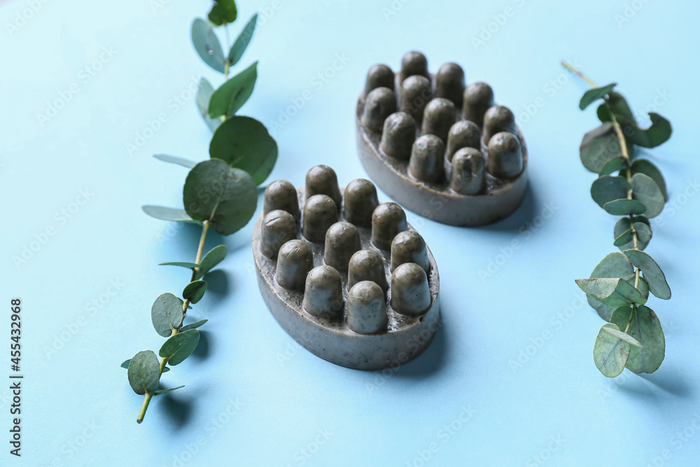 Massage soap bars and eucalyptus branches on color background