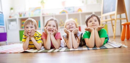 Wall Mural - Group of children lying on the floor and looking in the camera.