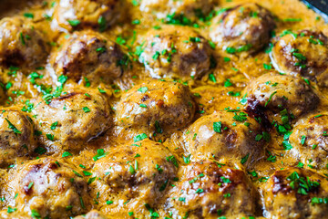 Wall Mural - Swedish meatballs in creamy sauce in black frying pan, gray background. Scandinavian food concept.