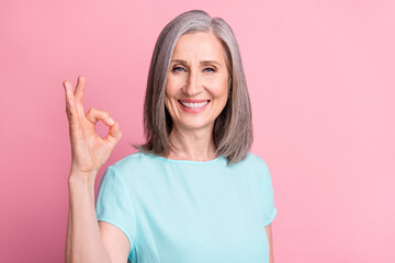 Sticker - Photo of impressed old grey hairdo lady show okey sign wear teal blouse isolated on pink color background