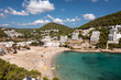 Aerial photo of the Spanish island of Ibiza showing the beautiful beach front and hotels and people on and the beach at Cala Llonga in the summer time in the Balearic Islands, Spain