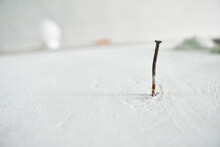White Textured Wall With Nailed, Space For Text. Textured Rusty And Stained Nail