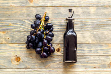 Bottle of balsamic vinegar with bunch of fresh grapes