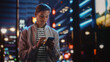 © Gorodenkoff - Handsome Man Using Smartphone Walking Through Night City Full of Neon Colors and Entertainment. Stylish Young Man Using Mobile Phone, Posting on Social Media, Online Shopping, Texting on Dating App
