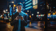 © Gorodenkoff - Man Using Smartphone Walking Through Night City Street Full of Neon Light. Smiling Stylish Man Using Mobile Phone, Social Media, Online Shopping, Texting on Dating App.