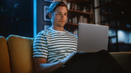 Poster - Man Using Laptop at Home Office, Does Remote Work in the Evening. Handsome Male Sitting on Sofa Works On Computer, Brainstorms Creative Project, does Online Shopping, Browsing Internet.